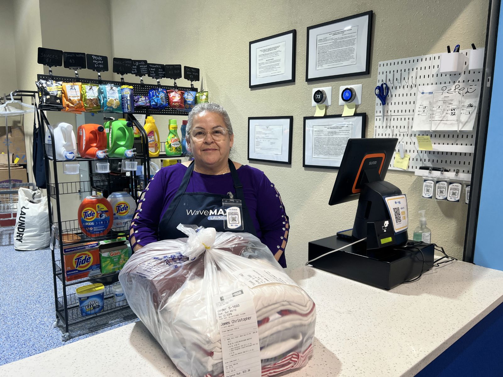 Grace at the WaveMAX front counter with a finished wash & fold order ready for pickup