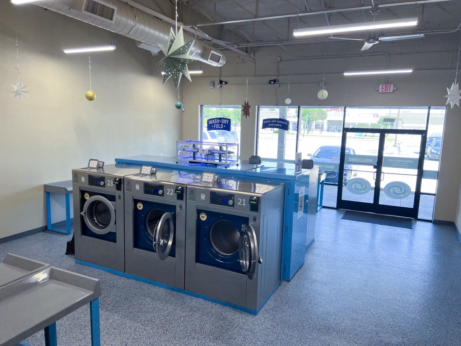 Brand-new Electrolux washers with WASH·DRY·FOLD signage and view of the storefront